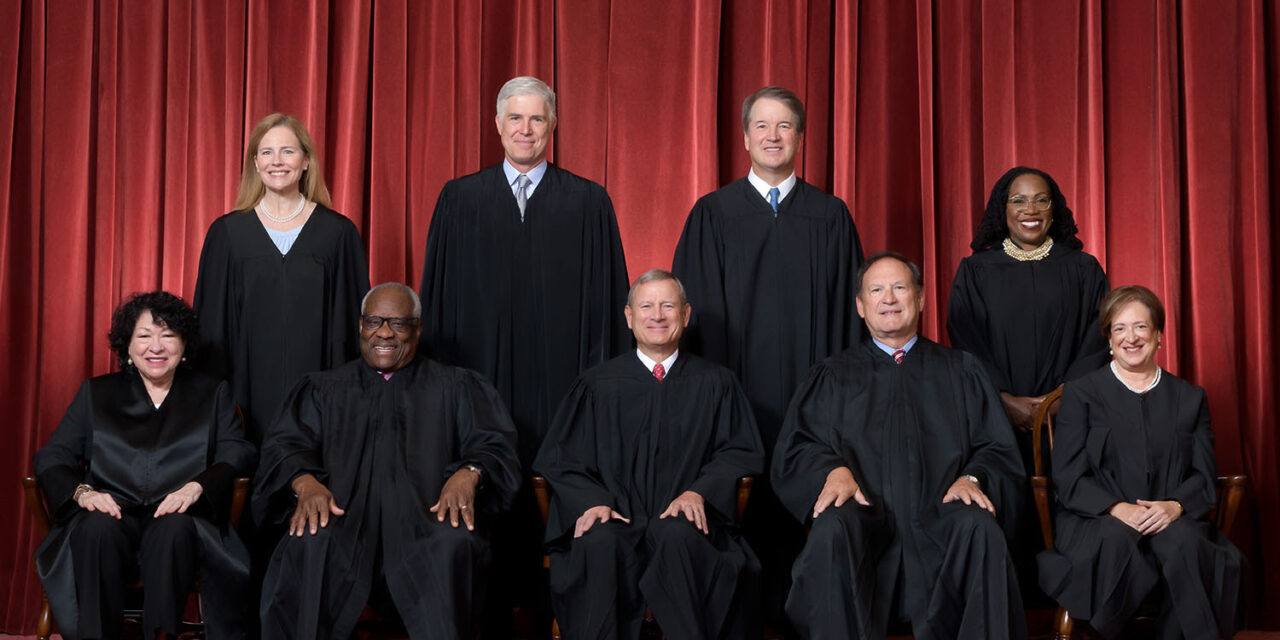 Formal group photograph of the Supreme Court as it was been comprised on June 30, 2022 after Justice Ketanji Brown Jackson joined the Court. The Justices are posed in front of red velvet drapes and arranged by seniority, with five seated and four standing.Seated from left are Justices Sonia Sotomayor, Clarence Thomas, Chief Justice John G. Roberts, Jr., and Justices Samuel A. Alito and Elena Kagan. Standing from left are Justices Amy Coney Barrett, Neil M. Gorsuch, Brett M. Kavanaugh, and Ketanji Brown Jackson.Credit: Fred Schilling, Collection of the Supreme Court of the United States